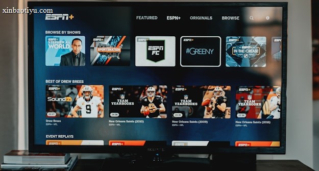 A television screen displaying the ESPN+ streaming interface with various sports-related shows and categories. The screen includes sections such as 'Browse by Shows' and 'Best of Drew Brees' with thumbnails of sports programs featuring athletes in action and analysts.