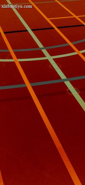A sports court with intersecting lines in orange and blue, creating geometric patterns on a reddish-brown surface.